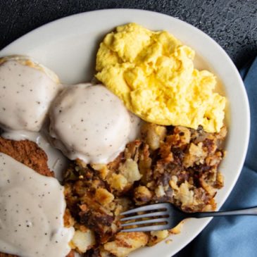A plate of breakfast from Chompie's with biscuits and gravy, chicken fried steak, potatoes, and eggs