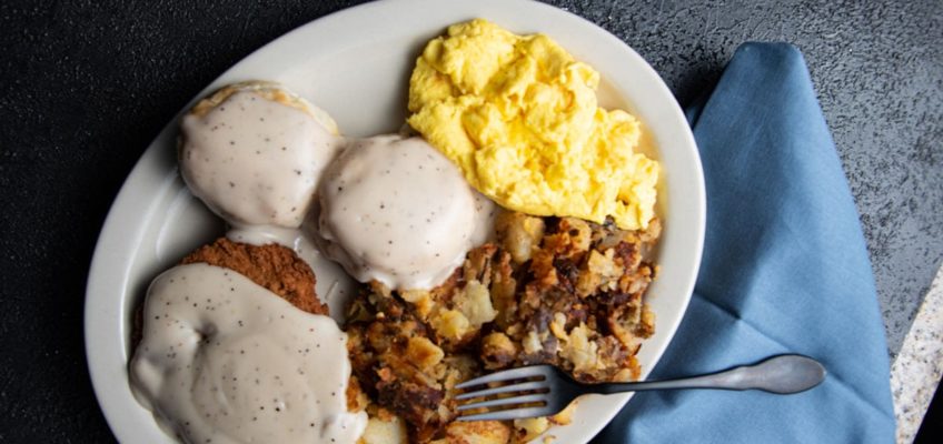 A plate of breakfast from Chompie's with biscuits and gravy, chicken fried steak, potatoes, and eggs