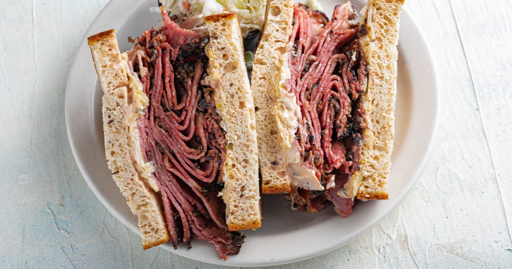 Chompie's keto-friendly Reuben Sandwich cut in half on a plate