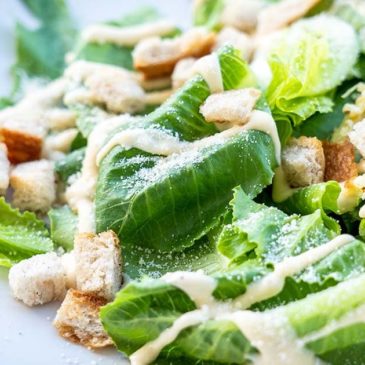 Fresh Caesar Salad on a white plate being served at a restaurant